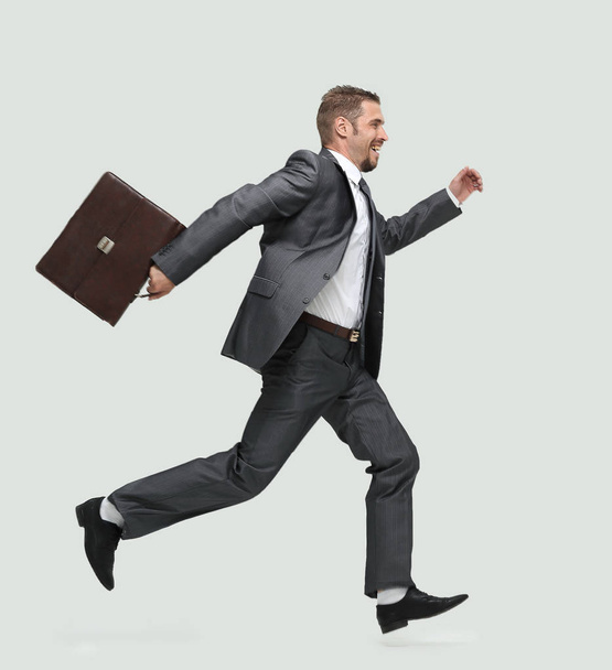 side view.cheerful businessman with briefcase stepping forward - Foto, afbeelding