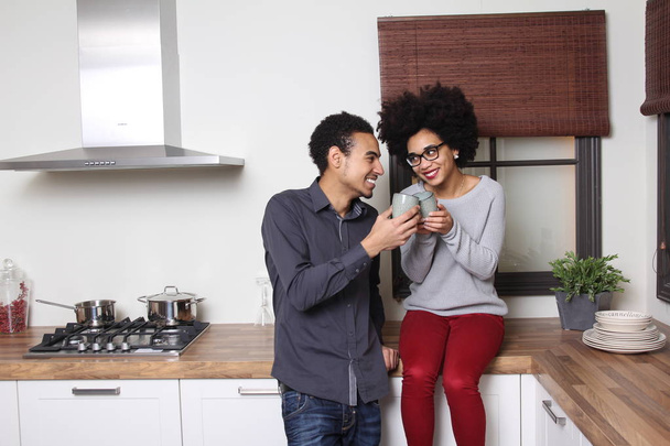 Afro-american man and woman is drinking tea on kitchen - Photo, Image