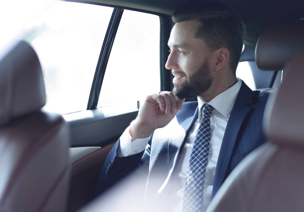 Homme d'affaires souriant assis sur le siège arrière d'une voiture
 - Photo, image