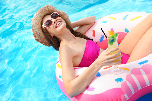 Молодая женщина с коктейлем в бассейне в солнечный день
 - Фото, изображение