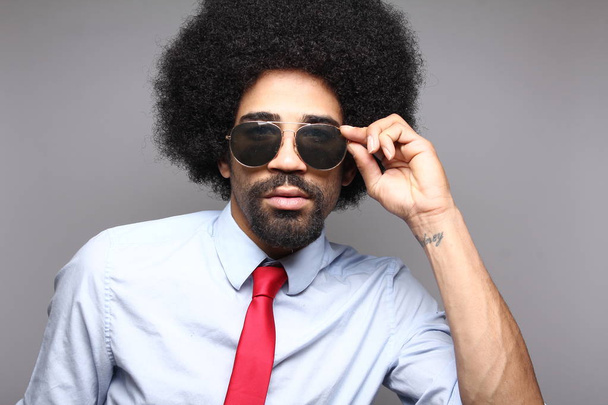 serious  afro businessman in sunglasses in front of gray background - Fotoğraf, Görsel