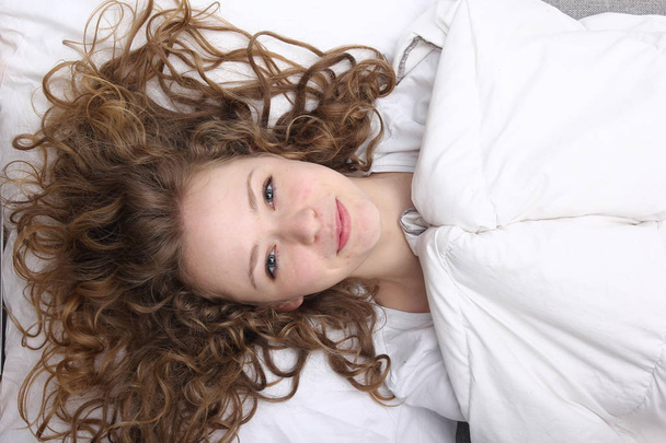 Beautiful young girl is lying on bed and smiling - Foto, immagini