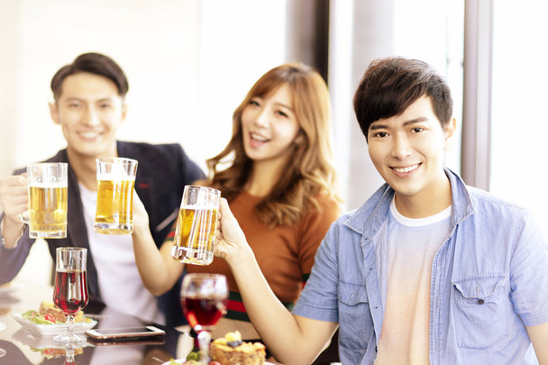 onnellisia nuoria ystäviä juo olutta ravintolassa
. - Valokuva, kuva