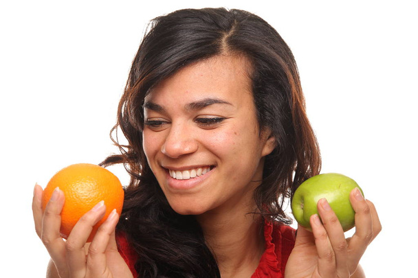 Beautiful afro-american woman is holding apple and orange - Foto, imagen