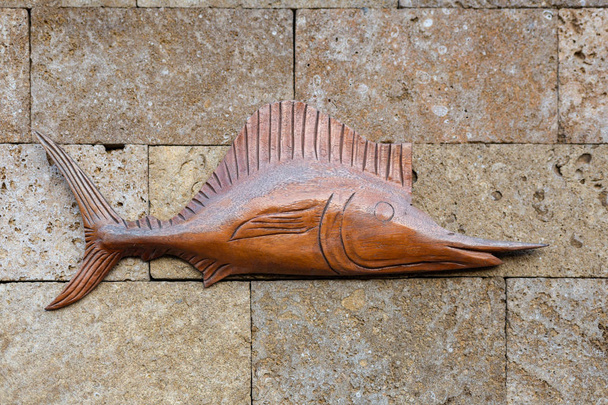 Wooden fish on a stone wall. - Foto, imagen