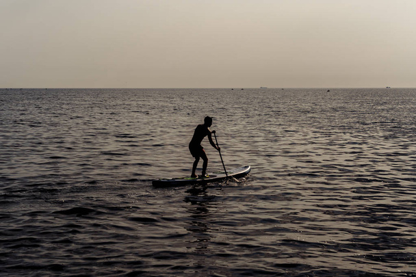 Pás em pé, silhueta de homem na praia ao pôr-do-sol. SUP surf
. - Foto, Imagem