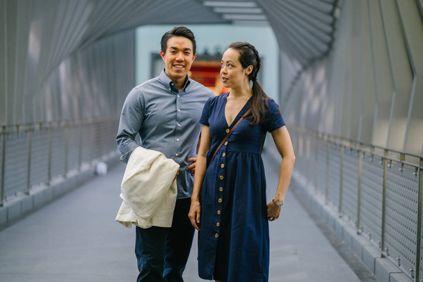 Portrait of an Asian Chinese couple on a date over the weekend. The man is young, handsome and well-dressed and the woman is wearing an elegant summer dress. They are  on a bridge. - Photo, Image