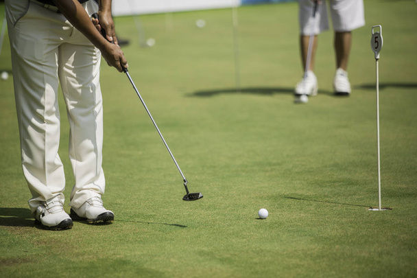 Golf player at the putting green hitting ball into a hole - Fotografie, Obrázek