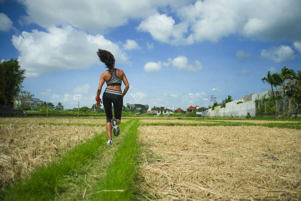 Hátulnézet a fiatal futó nő vonzó és fitt test, futás a szabadban edzés off road pálya zöld táj háttér jogging fitness gyönyörű és egészséges életmód - Fotó, kép