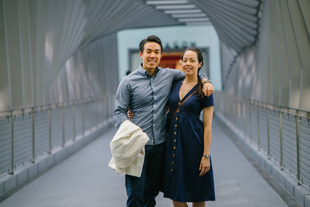 Portrait of an Asian Chinese couple on a date over the weekend. The man is young, handsome and well-dressed and the woman is wearing an elegant summer dress. They are  on a bridge. - Fotoğraf, Görsel