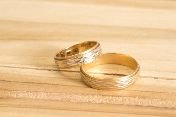 Два золотых обручальных кольца на деревянном столе
 - Фото, изображение