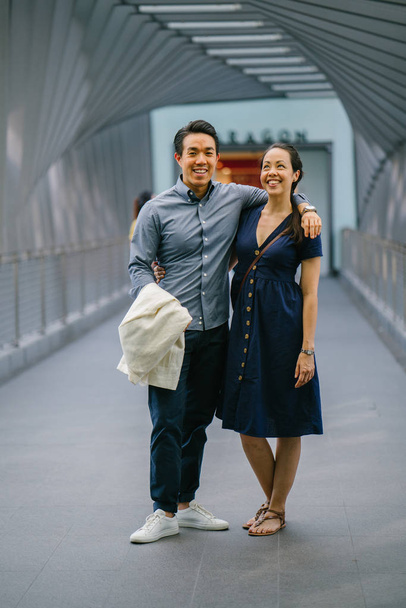 Retrato de una pareja de chinos asiáticos en una cita durante el fin de semana. El hombre es joven, guapo y bien vestido y la mujer lleva un elegante vestido de verano. Están en un puente.
. - Foto, Imagen