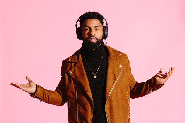 Cool African American man with beard, and headphones. isolated on pink studio background. Hands to the sides. - Foto, Imagem