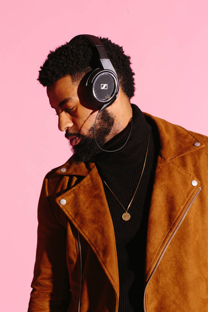 Stylish, handsome and cool African American man with beard, listening to music, isolated on pink studio background - Фото, изображение
