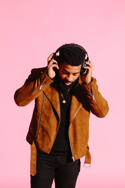 Stylish, handsome and cool African American man with beard, listening to music, isolated on pink studio background - Φωτογραφία, εικόνα