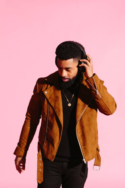 Stylish, handsome and cool African American man with beard, listening to music, isolated on pink studio background - Foto, Imagen