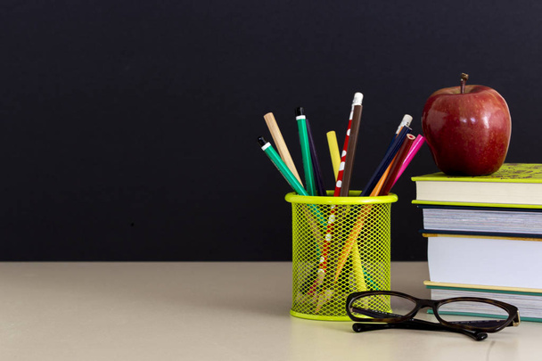Okula dönüş sağlar. Kitap ve kara tahta arka plan üzerinde kırmızı elma. Kalem ile natürmort. Kopya alanı. - Fotoğraf, Görsel