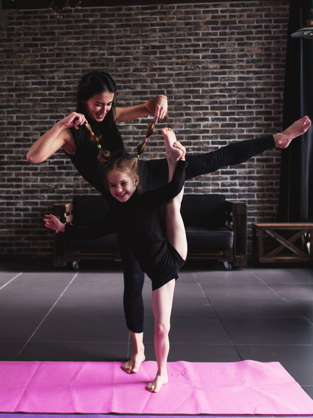 Mãe e pequena filha fazendo pé perna dividida alongamento exercício mantendo o equilíbrio
 - Foto, Imagem