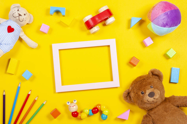 Bebek Çocuk oyuncakları ve arka plan boş çerçeve renkli ahşap yumuşak oyuncak sarı arka plan üzerinde renkli kalemler. Üstten görünüm - Fotoğraf, Görsel
