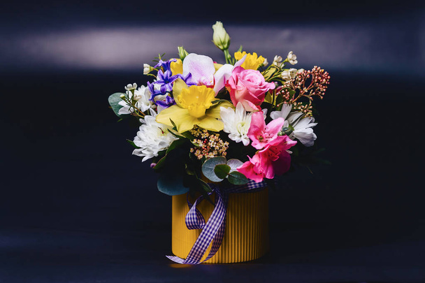 gekleurde bloemboeket in mand op donkere achtergrond - Foto, afbeelding