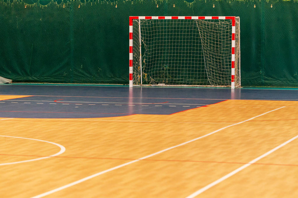 Gym for playing futsal, mini-football. Folded wooden parquet on the field of hall for mini-football. Futsal ball and bright line markings on the floor. Floor sports hall with bright lines of marking - Fotografie, Obrázek