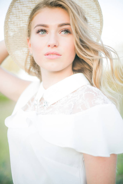 Beautiful young girl with blond long hair in summer in a field on a sunny day - Fotografie, Obrázek