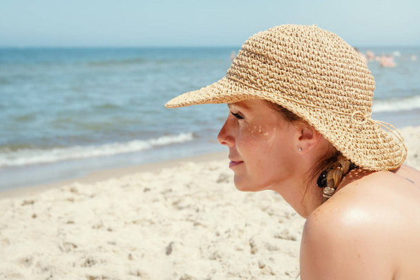 woman in a hat is looking from the beach to the sea in the summer - Fotó, kép