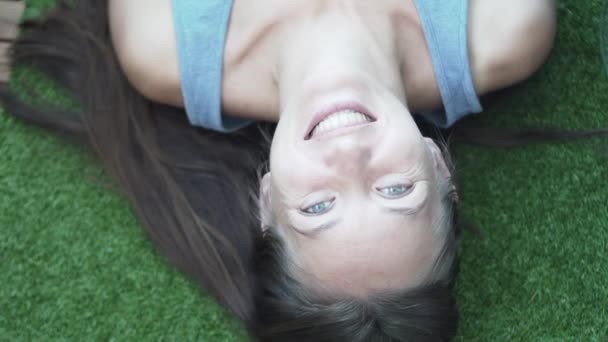 The girl lies on an artificial green lawn. She is laughing - Video, Çekim
