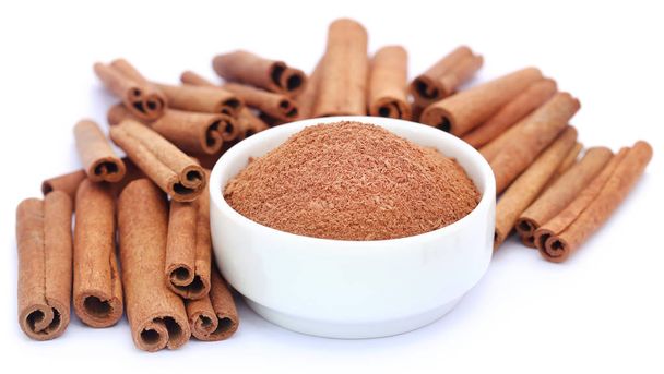 Bunch of some fresh aromatic cinnamon with powder spice over white background - Photo, Image