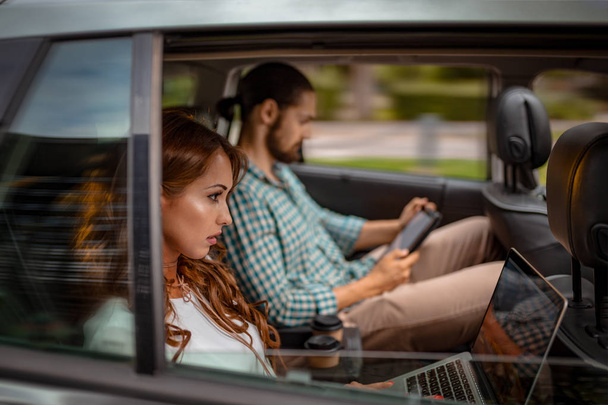 partenaires d'affaires assis sur le siège arrière en voiture et travaillant sur ordinateur portable et tablette PC en voyage d'affaires
   - Photo, image
