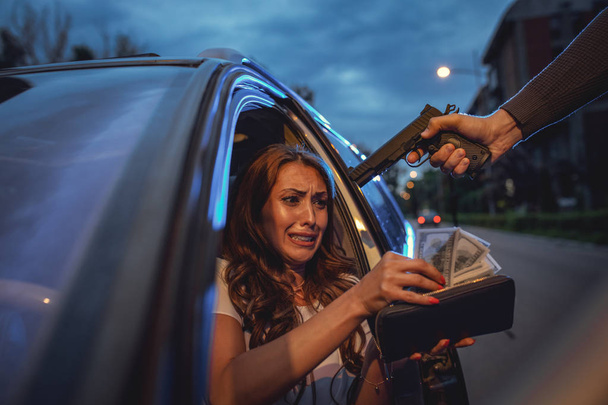 Tehlikeli suç adam silahla çalmak para korkmuş genç kadının üzerinde açık otopark - Fotoğraf, Görsel