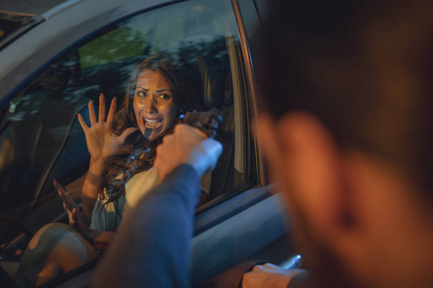nainen tunne shokki ja pelottava autossa, kun rosvo ryöstää hänet aseella
   - Valokuva, kuva