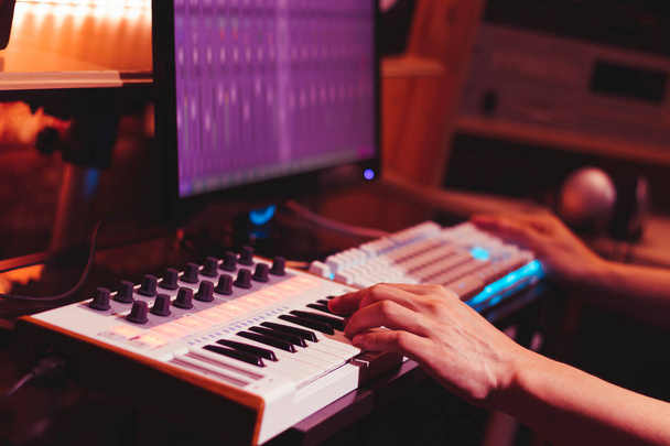 musician hands playing midi keyboard synthesizer for recording music on computer in digital sound studio - Foto, immagini