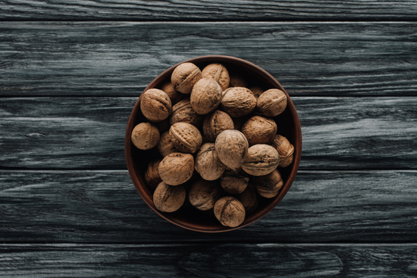 walnuts in wooden bowl on dark wooden background - Фото, изображение