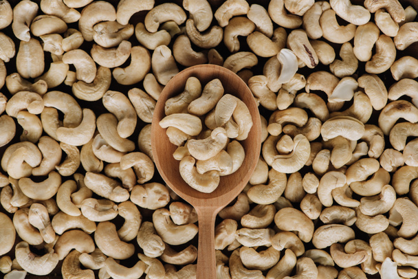 Top view of tasty cashew and one wooden spoon - Photo, Image