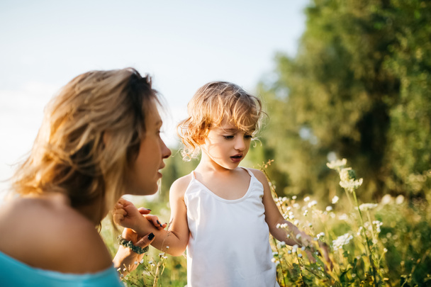 μητέρα και παιδί που βλέπει λουλούδια στο πράσινο πεδίο - Φωτογραφία, εικόνα