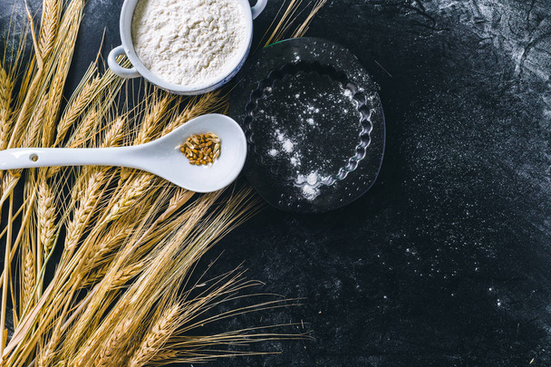 Wheat ears and flour on black background - Foto, Bild