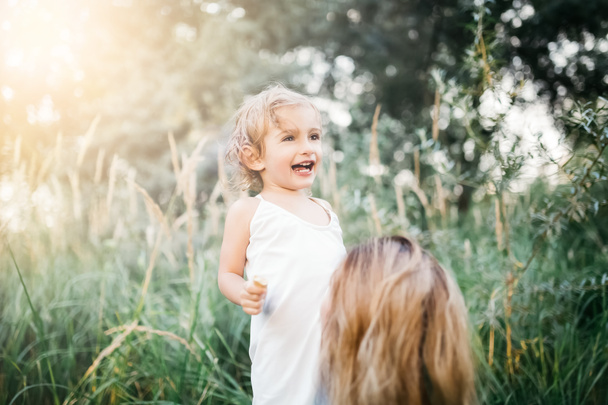 smiling adorable daughter and mother in green grass - Foto, Imagen