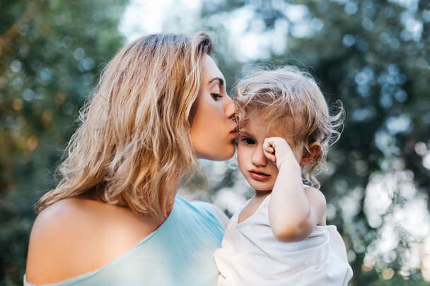 mother kissing crying daughter outdoors - Valokuva, kuva