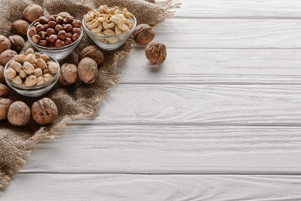 Valikoima pähkinät lasi kulhot valkoinen puinen pöytälevy
 - Valokuva, kuva