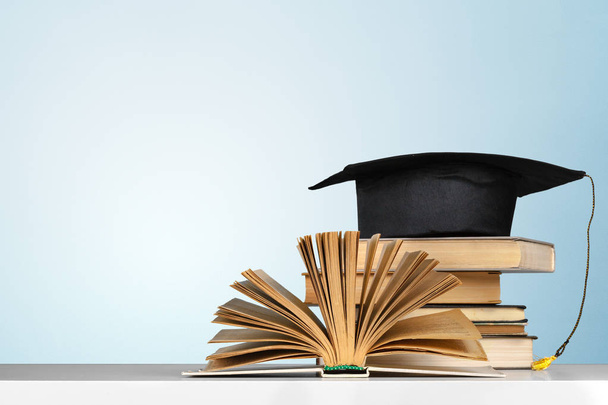 books and mortarboard on wooden table - Foto, immagini