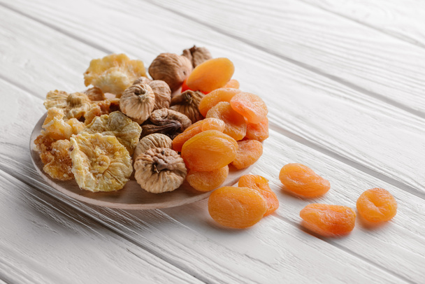 Mixed dried fruits on white plate on wooden table  - Photo, Image