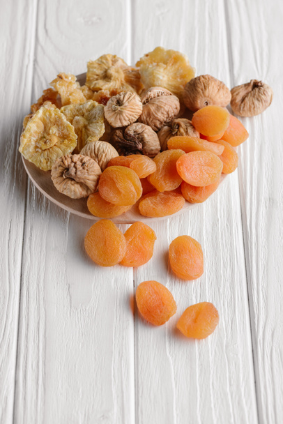 Variety of dried fruits on white plate on wooden surface - Photo, Image