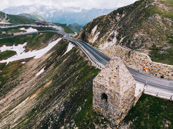 Bird's eye view of road in snowy mountains under cloudy sky. Aerial view of scenic touristic route in Austria with name Grossglockner High Alpine Road. Some of part of Hochtor Pass - Fotoğraf, Görsel