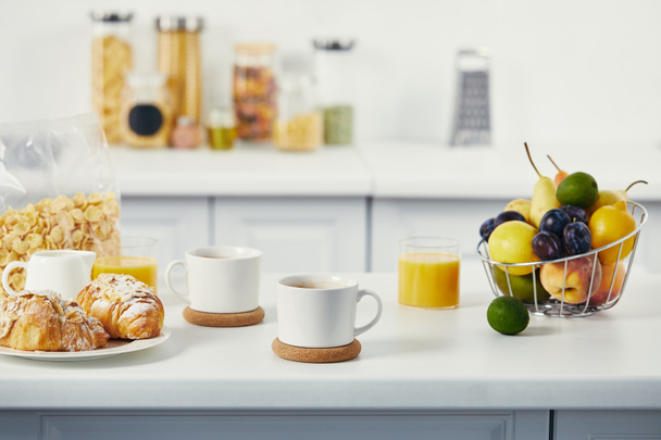 close up view of cups of coffee and croissants for breakfast on white tabletop in kitchen - Photo, Image