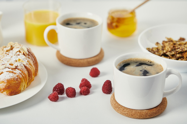 close up view of tasty breakfast with cups of coffee and croissant on white surface - Photo, Image