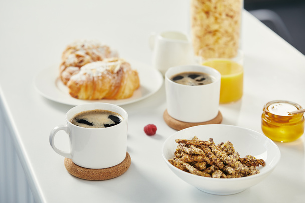 vista de cerca de las tazas de café, miel y croissants para el desayuno en la superficie blanca
  - Foto, Imagen