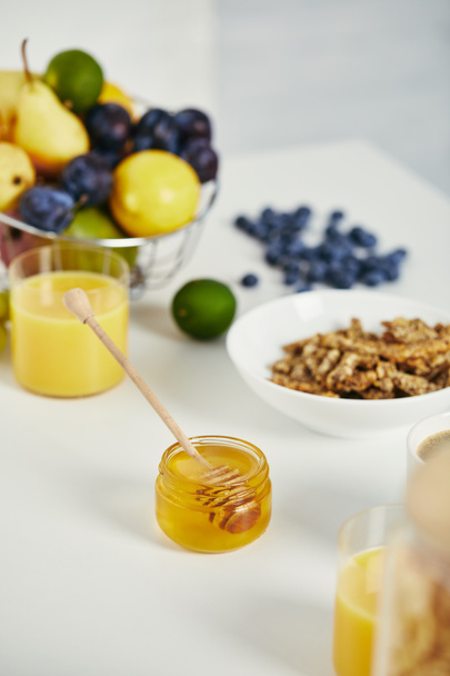 Close-up van honing, vers fruit en glas sap voor het ontbijt op witte ondergrond - Foto, afbeelding