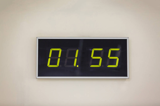 Reloj digital negro sobre fondo blanco que muestra el tiempo de una hora 55 minutos
 - Foto, imagen