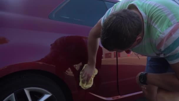 Młody człowiek kaukaski mycia jego samochodu na myjni samoobsługowej. Mycie samochodu. - Materiał filmowy, wideo